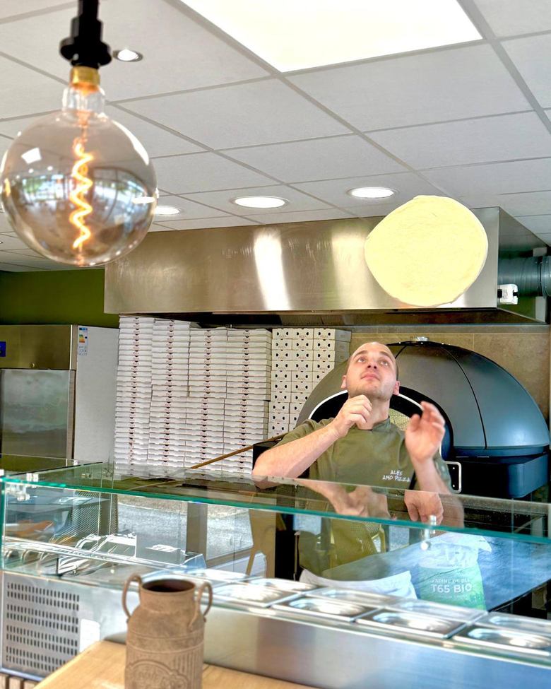 Alex fait tourner la pâte à pizza chez AMO Pizza