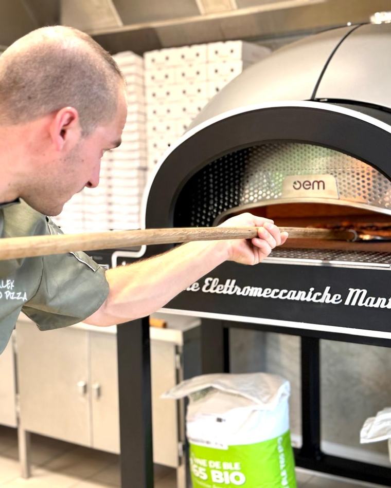 Alex, pizzaïolo d'AMO Pizza, enfourne une pizza